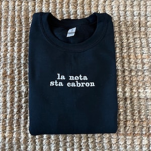 May include: Black sweatshirt with white embroidered text that reads "la neta sta cabron".