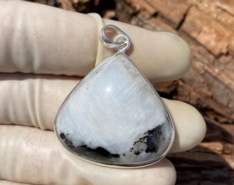 May include: A white and black gemstone pendant with a silver setting. The pendant is in the shape of a triangle.