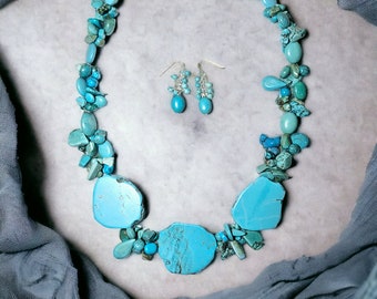 Puede incluir: Un collar turquesa con una cadena de plata y piedras turquesa grandes. El collar se combina con pendientes turquesa a juego.