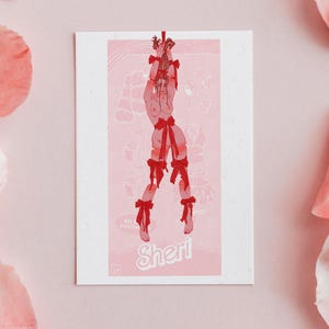 May include: A pink and red illustration of a person tied up with red ribbons. The person is standing with their arms above their head. The illustration is on a white card with the text "Sheri" at the bottom.