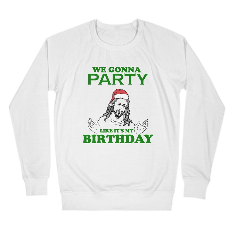 May include: White long-sleeve sweatshirt with green text that reads "We gonna party like it's my birthday". A cartoon image of Jesus wearing a Santa hat is in the center of the text.