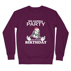 May include: Purple long-sleeved sweatshirt with a white graphic of a man wearing a Santa hat and the text "WE GONNA PARTY LIKE IT'S MY BIRTHDAY"