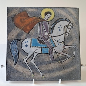 Puede incluir: Azulejo cerámico cuadrado con un caballero a caballo. El caballero lleva una armadura morada y una capa roja, con un halo dorado. El caballo es blanco con detalles azules, sobre un fondo gris y azul.