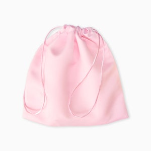 May include: A pink drawstring bag made of satin fabric. The bag has a simple design and is perfect for storing small items.