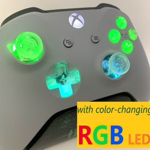 May include: A white Xbox controller with green and blue LED lights. The controller has color-changing RGB LEDs.