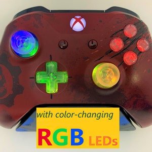 May include: A red Xbox controller with a Gears of War design. The controller has color-changing RGB LEDs on the buttons and the text "with color-changing RGB LEDs" is printed on a yellow sticker.