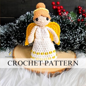 Puede incluir: Una muñeca de ángel hecha a mano con alas amarillas, un vestido blanco y un moño castaño claro. La muñeca se exhibe sobre una rodaja de madera con un fondo blanco y esponjoso. Las palabras "CROCHET PATTERN" están escritas en la imagen.