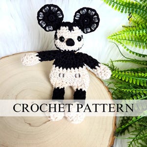Pode incluir: Boneca Mickey Mouse de crochê feita à mão em preto, creme e branco. A boneca tem orelhas pretas grandes com detalhes prateados, um nariz preto e um corpo creme. O texto "CROCHET PATTERN" é exibido na parte inferior da imagem.
