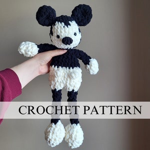 Puede incluir: Patrón de crochet para un juguete de peluche Mickey Mouse blanco y negro. El juguete está de pie con los brazos extendidos y tiene un cuerpo largo y delgado.