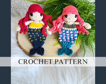 May include: Two handmade crochet mermaid dolls with red and pink hair, holding hands. One has a yellow and blue top, the other a green top. Both have blue tails with bead accents. The dolls are displayed on a wooden slice with the words "CROCHET PATTERN" below.