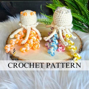 May include: Two crocheted jellyfish with beaded tentacles sit on a wooden slice. One has orange beads, the other has blue, pink, and yellow beads. The text "CROCHET PATTERN" is displayed below the jellyfish.