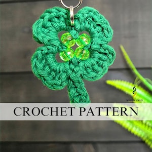 May include: A green crocheted four-leaf clover keychain with a silver ring. The clover is embellished with four green beads in the center. The text "CROCHET PATTERN" is displayed on a white banner.