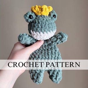 May include: A crocheted green frog wearing a yellow crown. The frog is holding its arms out and has a white crocheted mouth. CROCHET PATTERN is written in white text on a light blue background.