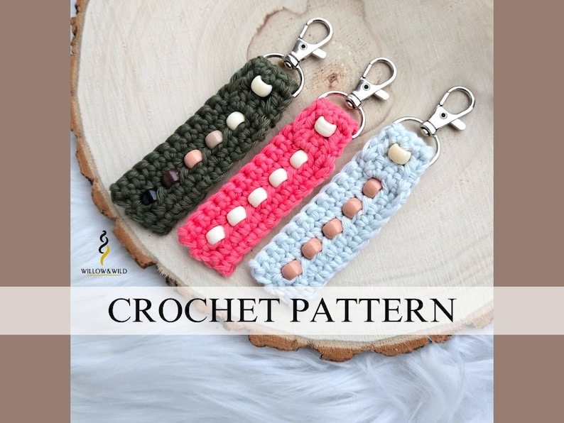 May include: Three crocheted keychains with different colored yarn and beads. The keychains are green, pink, and blue. The text "CROCHET PATTERN" is visible at the bottom of the image.