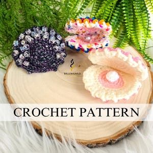 以下が含まれることがあります： 真珠が入った、3つの編み物でできた貝殻。貝殻はそれぞれ異なる色と模様をしています。貝殻は木の表面に置かれています。画像には「CROCHET PATTERN」と書いてあります。