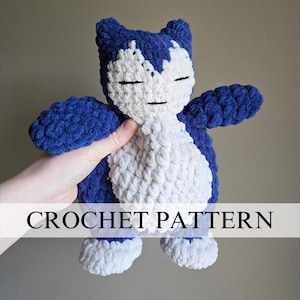 Könnte beinhalten: Ein gehäkeltes blaues und weißes Plüschtier, das einem Pokemon-Charakter ähnelt. Das Spielzeug hat ein weißes Gesicht mit schwarzen Augen und einen blauen Körper mit weißen Akzenten. Der Text "CROCHET PATTERN" ist am unteren Rand des Bildes sichtbar.