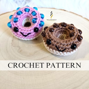 Könnte beinhalten: Zwei gehäkelte Donuts, einer rosa mit blauen Streuseln und einer braun mit Schokoladenstückchen. Beide Donuts haben ein lächelndes Gesicht.