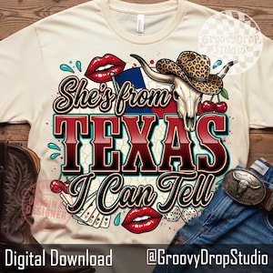 May include: Cream-colored t-shirt with a graphic design featuring the text "She's from TEXAS I Can Tell". The design includes a steer skull, a cowboy hat, cherries, and playing cards. The shirt also has red lips and a Texas flag.