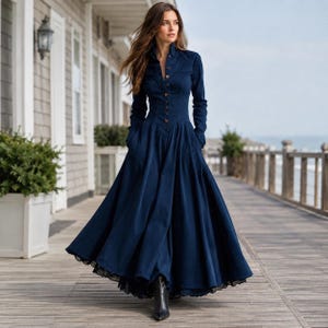 May include: A long-sleeved navy blue maxi dress featuring a button-down front, a fitted bodice, and a full, flowing skirt. The hemline is accented with a delicate black lace trim, and the dress is paired with black ankle boots.