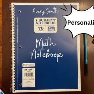 Könnte beinhalten: Ein blaues 1-Fach-Notizbuch mit 70 Blatt mit breitem Lineatur. Das Notizbuch ist mit dem Namen Avery Smith und den Worten "Math Notebook" personalisiert.