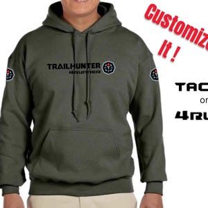 Puede incluir: Sudadera con capucha verde oliva con el texto "TRAILHUNTER 4runner" y un logotipo. Las palabras "Customize It!" están en rojo, con "TACOMA or 4RUNNER" en negro. La sudadera tiene un bolsillo delantero y una capucha.