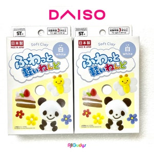 Könnte beinhalten: Zwei Packungen weiße Soft Clay, mit Illustrationen eines Pandas, Kuchens, Schmetterlings und Blumen. Die Verpackung enthält japanischen Text und den Markennamen "DAISO". Die Packungen sind mit "Soft Clay" und "White" beschriftet.