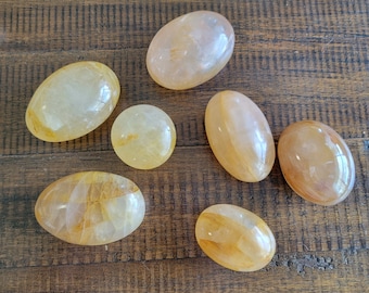 Puede incluir: Siete piedras de citrino lisas, de forma ovalada, de color amarillo claro. Las piedras están pulidas y tienen una apariencia translúcida.