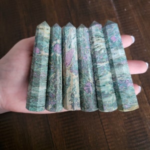 May include: Seven green and pink striped crystal wands with pointed ends.