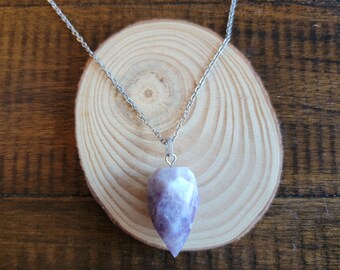 May include: A silver chain necklace with a purple amethyst crystal pendant in the shape of a point.