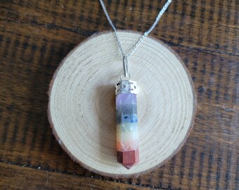 Könnte beinhalten: Eine silberne Kettenkette mit einem sieben-Chakra-Kristall-Anhänger. Der Anhänger ist ein spitzer, mehrfarbiger Kristall mit einer silbernen Kappe oben.