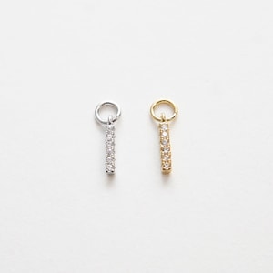 May include: Two dainty bar charms with a row of clear cubic zirconia stones. One charm is silver and the other is gold.