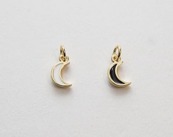 May include: Two gold crescent moon charms, one with white enamel and one with black enamel.