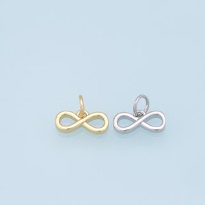 May include: Two infinity symbol charms, one gold and one silver, on a light blue background.