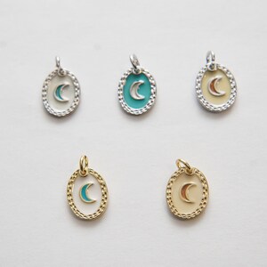 May include: Five oval-shaped charms with a crescent moon design. The charms are made of silver and gold metal and have a white enamel background. The crescent moons are turquoise, orange, and gold.