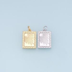 May include: Two square-shaped pendants with a sun design. One pendant is gold and the other is silver.