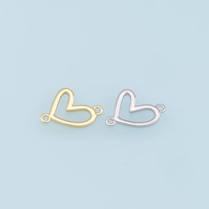 Può includere: Due ciondoli in metallo a forma di cuore con anelli a salto. Un ciondolo è dorato e l'altro è argentato.