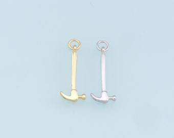 May include: Two hammer charms, one gold and one silver, with a loop at the top for attaching to a necklace or bracelet.