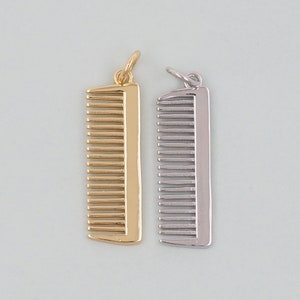 Puede incluir: Dos colgantes con forma de peine. Uno es dorado, el otro plateado. Ambos tienen un lazo en la parte superior para sujetarlos a una cadena o pulsera. Los peines tienen dientes espaciados uniformemente y forma rectangular.