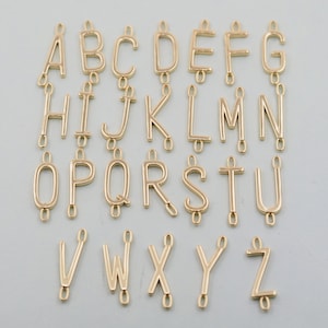 May include: Gold-toned metal alphabet letter charms. Each letter is a separate charm with a loop at the top for attaching to a necklace, bracelet, or other jewelry.