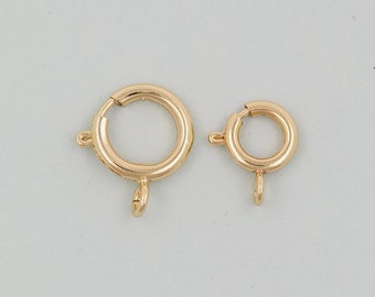 May include: Two gold-toned metal jump rings with a spring clasp. The larger ring is about 1 inch in diameter and the smaller ring is about 3/4 inch in diameter.