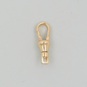 May include: A gold-toned metal watch chain clasp with a loop and a square-shaped end.