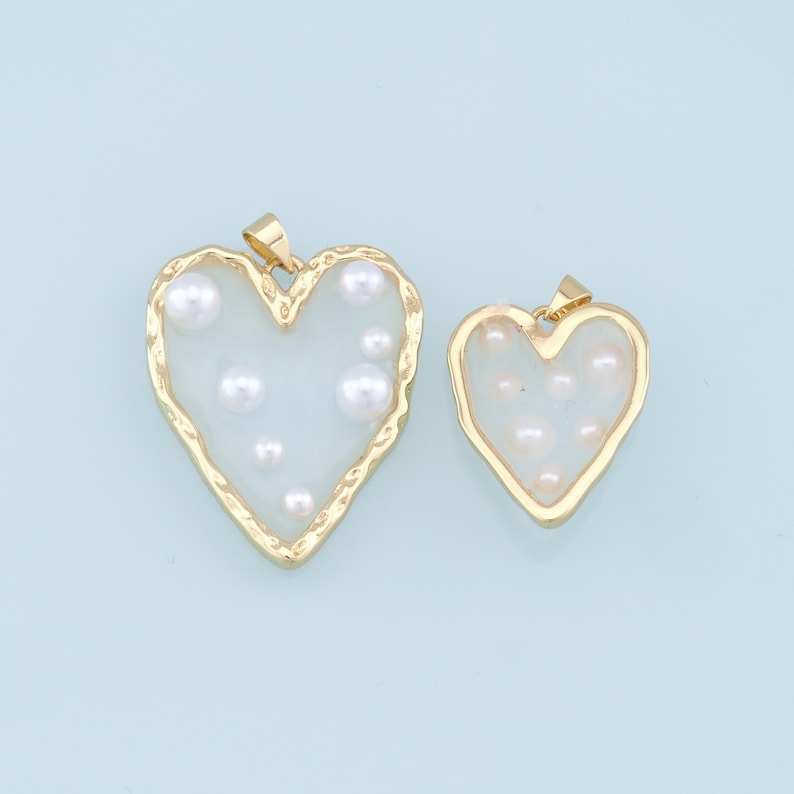 May include: Two gold heart-shaped pendants with clear glass and white pearl accents.