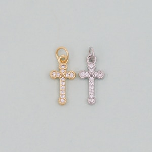May include: Two small cross charms, one gold and one silver, both with clear crystal accents.