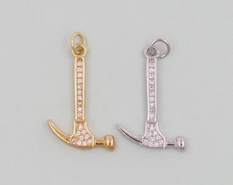 May include: Two silver and gold hammer charms with clear crystal accents. The charms are on a light blue background.