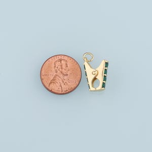 May include: Gold-tone clasp with green stones, next to a US penny for size comparison.