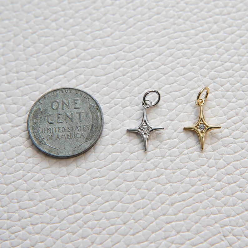 May include: Two silver and gold star charms with a single clear rhinestone in the center of each star.