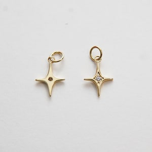 May include: Two gold star charms with a small clear rhinestone in the center. One charm has a hole at the top for attaching to a necklace or bracelet.