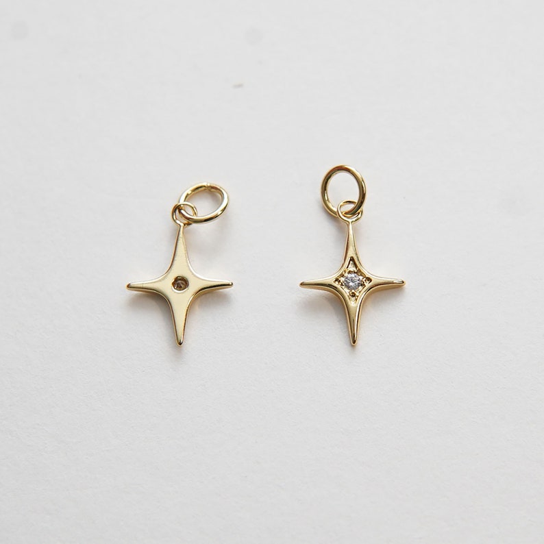 May include: Two gold star charms with a small clear rhinestone in the center. One charm has a hole at the top for attaching to a necklace or bracelet.