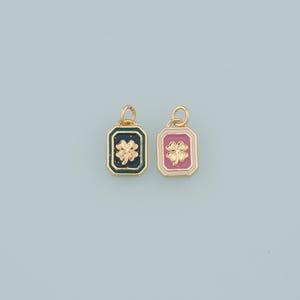 May include: Two gold-colored pendants with a rectangular shape and a four-leaf clover design. One pendant has a dark teal background with a gold border, and the other has a pink background with a gold border.