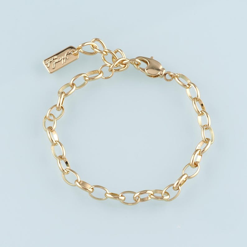May include: Gold-colored chain bracelet with oval links. The bracelet has a lobster clasp closure and an extender chain. A small rectangular tag with the word "Handmade" is attached to the chain.